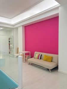 Renovated common area with a comfortable sofa and colorful pink wall at Jaleo Madrid Spanish school.