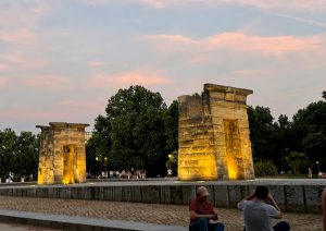 El Templo de Debod iluminado por la noche en Madrid, con una luz cálida que resalta la piedra.